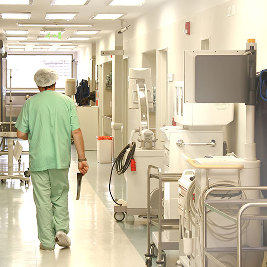 Doctor walking down hall of hospital lined with medical equipment