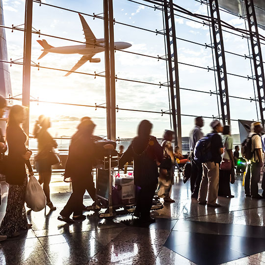 Busy airport with passengers walking by and airplane outside the window