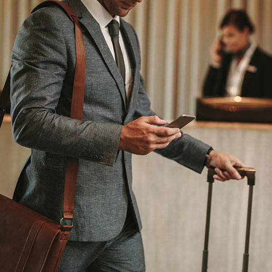 Man in suit holding smart phone and luggage