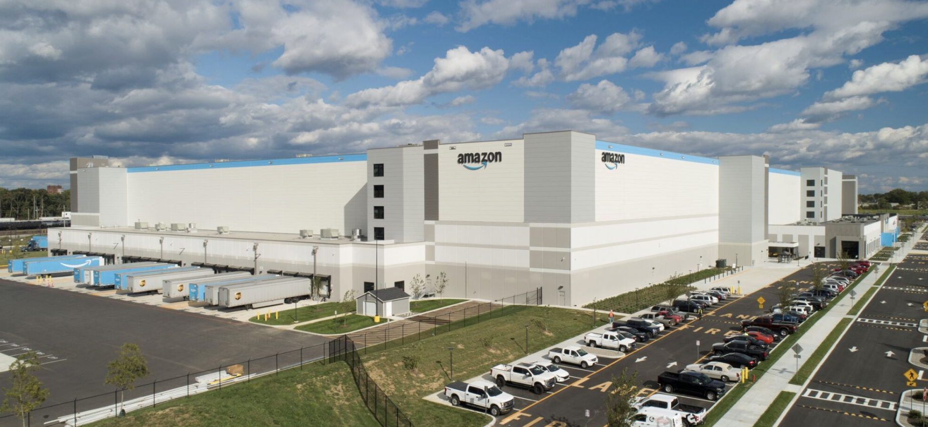 Amazon warehouse with full parking lot and trucks loading